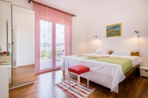 una camera con un grande letto e uno sgabello rosso di Apartment "On the beach" a Trogir