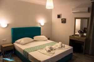 een slaapkamer met een bed met een blauw hoofdeinde en een spiegel bij Cielo Apartments in Poros