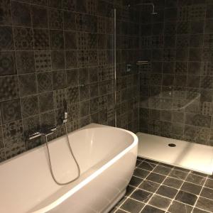 uma banheira branca na casa de banho com piso em azulejo em De Worfthoeve em Geel