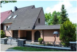 a house with a black roof and a person holding an umbrella at Teltow Ferienwohnung in Teltow