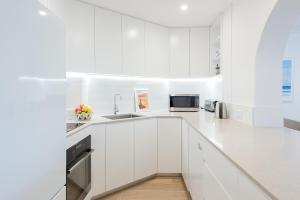 eine weiße Küche mit weißen Schränken und einem Waschbecken in der Unterkunft Right on Bondi in Sydney