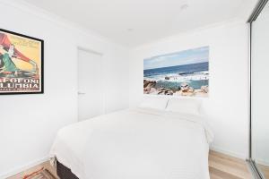 a white bedroom with a bed and a poster at Right on Bondi in Sydney