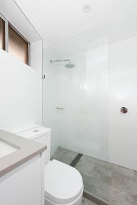 ein weißes Bad mit einem WC und einer Glasdusche in der Unterkunft Right on Bondi in Sydney