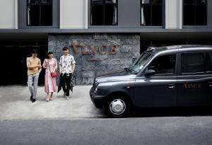 a group of people walking down a street next to a car at Vince Hotel Pratunam in Bangkok