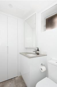 a white bathroom with a sink and a toilet at Right on Bondi in Sydney