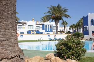 a swimming pool with palm trees and buildings at Apartamentos El Minarete in Roquetas de Mar