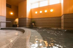a swimming pool with water in a building with a window at Nishitetsu Inn Kokura in Kitakyushu