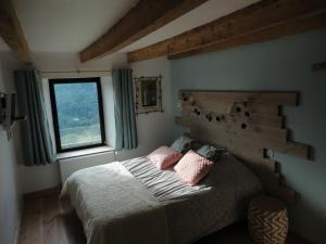 a bedroom with a bed with pink pillows and a window at La Ferme sous les Hiez in Cornimont