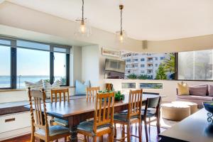 a dining room and living room with a table and chairs at Backup Powered Sea View Apartment on the Promenade in Cape Town