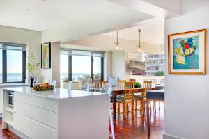 a kitchen and dining room with a view of the ocean at Backup Powered Sea View Apartment on the Promenade in Cape Town