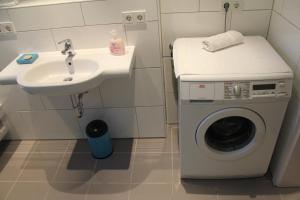 a bathroom with a washing machine and a sink at Le Coq in Rösrath