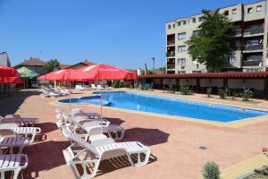 a pool with white chairs and umbrellas next to a building at Complex Trakite in Elkhovo