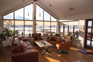 een woonkamer met banken, een tafel en ramen bij Great View Guesthouse in Eyjafjaroarsveit