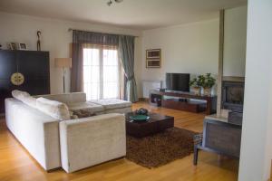 a living room with a white couch and a tv at Casa dos capuchos in Viana do Castelo