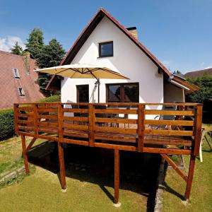 ein Haus mit einem Regenschirm auf einer Bank in der Unterkunft Chata Dandelion in Černá v Pošumaví