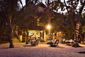マラパスクア島にあるAngelina Beach Resort & Italian Restaurant Malapascuaの夜はビーチのテーブルと椅子付きのレストラン