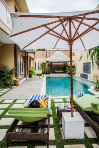 a person laying in a chair under an umbrella next to a swimming pool at O Villas Seminyak - 2026 Earlybirds ON SALE! in Seminyak