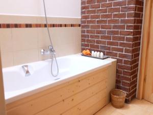 a bathroom with a tub and a brick wall at Cozy Cottage in ZeÅ‚wÄ gi with Fireplace in Zełwągi