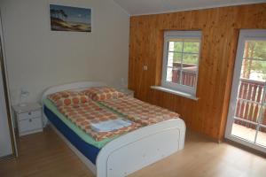 a bedroom with a bed with a wooden wall at Guesthouse "Nakvynė pas žveją" Vetrungiu Street 298-2 in Nida