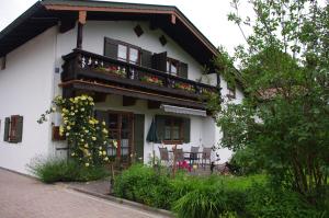 ein weißes Haus mit einem Balkon mit Blumen darauf in der Unterkunft Ferienwohnung Haus Alpenrebe in Schönau am Königssee