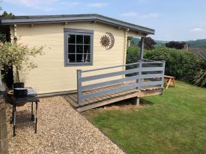 a small yellow house with a porch and a fence at Morlais Log Cabin in Lyme Regis