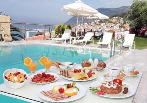 a table with plates of food next to a pool at Maria Plomari Apartments in Plomari