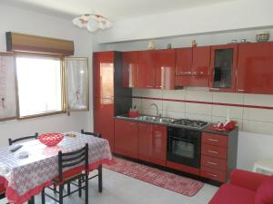 une cuisine avec des placards rouges et une table avec un chiffon de table dans l'établissement Appartamento Mare, à Sciacca