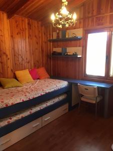 een slaapkamer met een bed, een bureau en een kroonluchter bij Casa-Apartamento Madera y Sol in Lubia