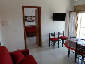 夏卡的住宿－Appartamento Mare，客厅配有红色的沙发、桌子和椅子