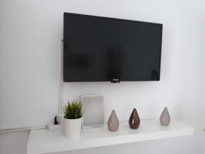 a tv on a white wall with vases on a shelf at Studio Old Center in Bucharest