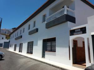 a white building with a balcony on a street at Hotel Boomerang in Valverde