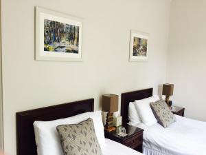 アバーフェルディにあるFernbank Houseのベッドルーム1室(ベッド2台付)が備わります。壁に2枚の写真が飾られています。