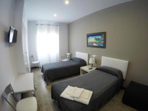 a hotel room with two beds and a television at Hostal Mediterráneo in Tossa de Mar