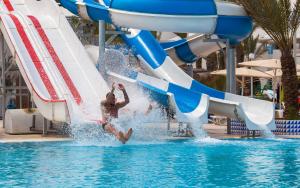 um homem a saltar de um escorrega aquático numa piscina em El Mouradi Djerba Menzel em Midoun