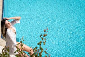 a woman sitting on the edge of a swimming pool at Dimamiel Malia Inn in Malia