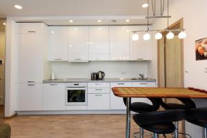 une cuisine avec des placards blancs et une table en bois dans l'établissement Smilčių Apartment, à Palanga