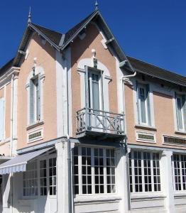 シャトライヨン・プラージュにあるThe Originals Boutique, Hôtel Victoria, Châtelaillon-Plageの大きなレンガ造りの建物で、バルコニーが付いています。