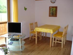 a living room with a table with a television and a table with chairs at Ferienhaus Beyer in Unterwössen