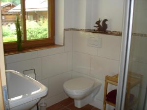 a bathroom with a toilet and a sink and a window at Ferienhaus Beyer in Unterwössen