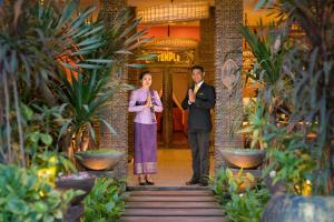 Um homem e uma mulher num corredor com plantas. em Golden Temple Hotel em Siem Reap