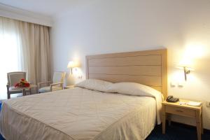 a hotel room with a large bed and two chairs at El Mouradi Mahdia in Mahdia