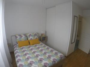 Dormitorio pequeño con cama con almohadas amarillas y moradas en Renoir Appartement, en Cagnes-sur-Mer