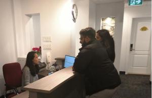 a group of people standing around a desk with a computer at Hotel Le Deville in Montreal