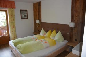 1 dormitorio con 1 cama con almohadas amarillas y amarillas en Familie Neunhäuserer, en Neustift im Stubaital