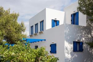 a white building with blue windows and trees at Aneli Luxury Villas-Villa Aegina in Aegina Town