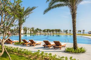 einen Pool im Resort mit Liegestühlen und Palmen in der Unterkunft Vinpearl Resort & Golf Nam Hoi An in Hoi An