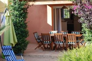 a patio with a table and chairs and an umbrella at VILLA LES NACRES A 400 MT DAL MARE in Porto-Vecchio