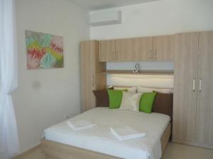 sypialnia z łóżkiem z zielonymi i białymi poduszkami w obiekcie Adel w Podgorze