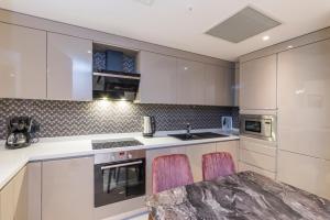 a kitchen with white cabinets and a table with pink chairs at Classy Suite Taksim in Istanbul
