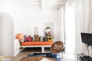 um sofá laranja num quarto branco com uma janela em Eclectic & Artistic house in Mykonos town em Míconos